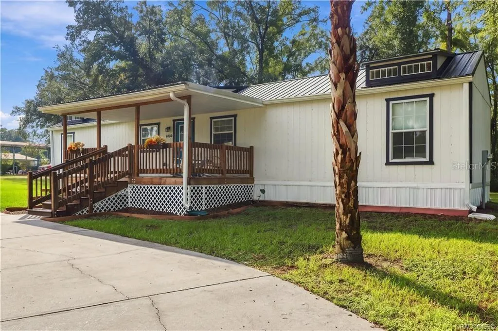 Exterior &amp; Front Porch – Another inviting perspective highlighting the covered wooden porch, contrasting exterior finishes &amp; beautiful palm tree.
