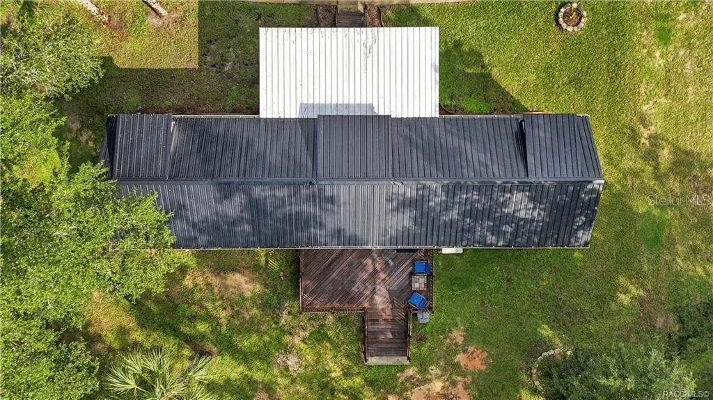 Aerial Roof &amp; Deck View – Bird's-eye perspective showcasing the METAL ROOF, covered front porch, spacious WOODEN REAR DECK &amp; surrounding green space.