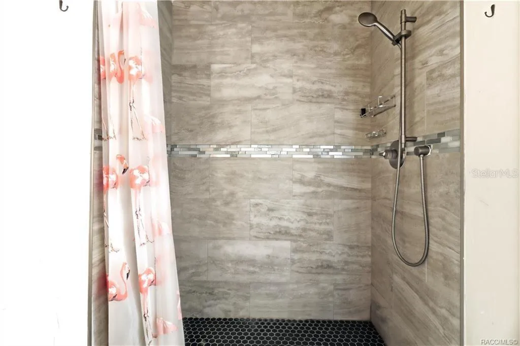 Tiled Walk-In Shower – Beautifully finished WALK-IN SHOWER featuring floor-to-ceiling tile, decorative mosaic accent band, pebble-style shower flooring &amp; handheld showerhead.