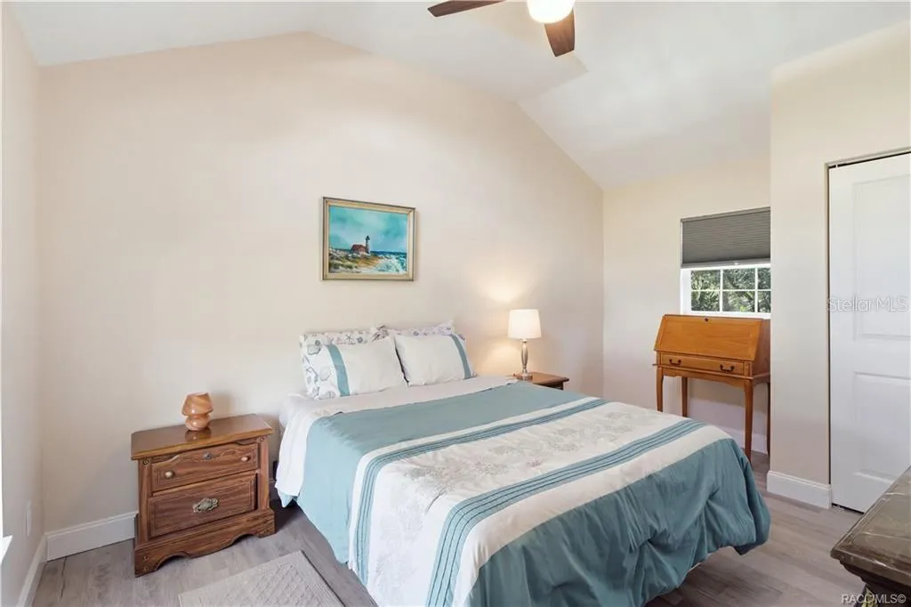 Primary Bedroom – Cozy &amp; inviting bedroom featuring VAULTED CEILINGS, luxury vinyl plank flooring, ceiling fan &amp; coastal-inspired furnishings.