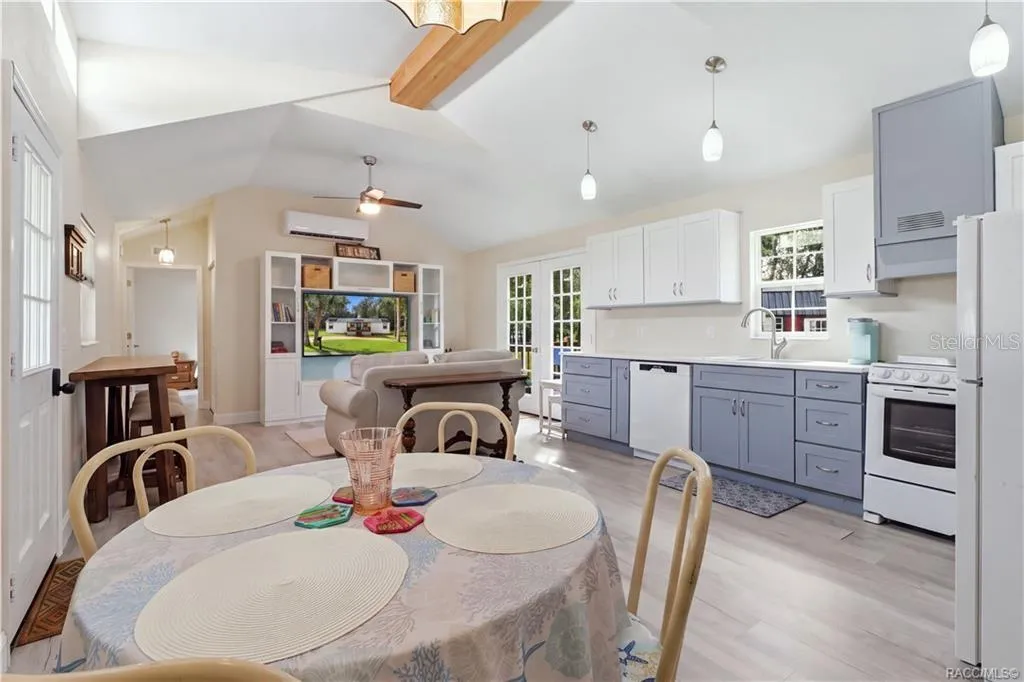 Open Living &amp; Kitchen Area – Light-filled OPEN FLOOR PLAN featuring VAULTED CEILINGS, attractive flooring, pendant lighting &amp; a beautifully coordinated kitchen.