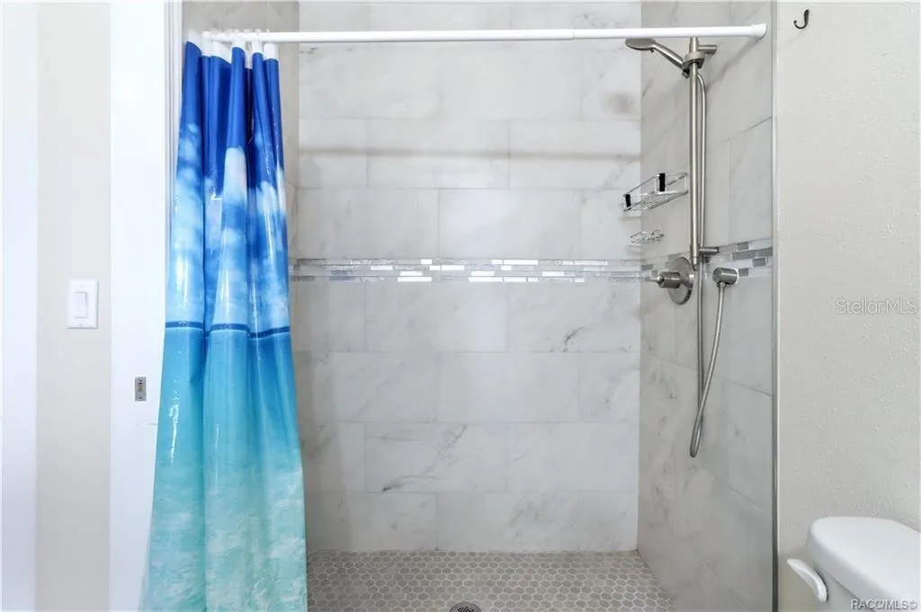Primary Bathroom Shower – Beautifully tiled WALK-IN SHOWER featuring marble-look wall tile, decorative mosaic accent &amp; handheld showerhead.