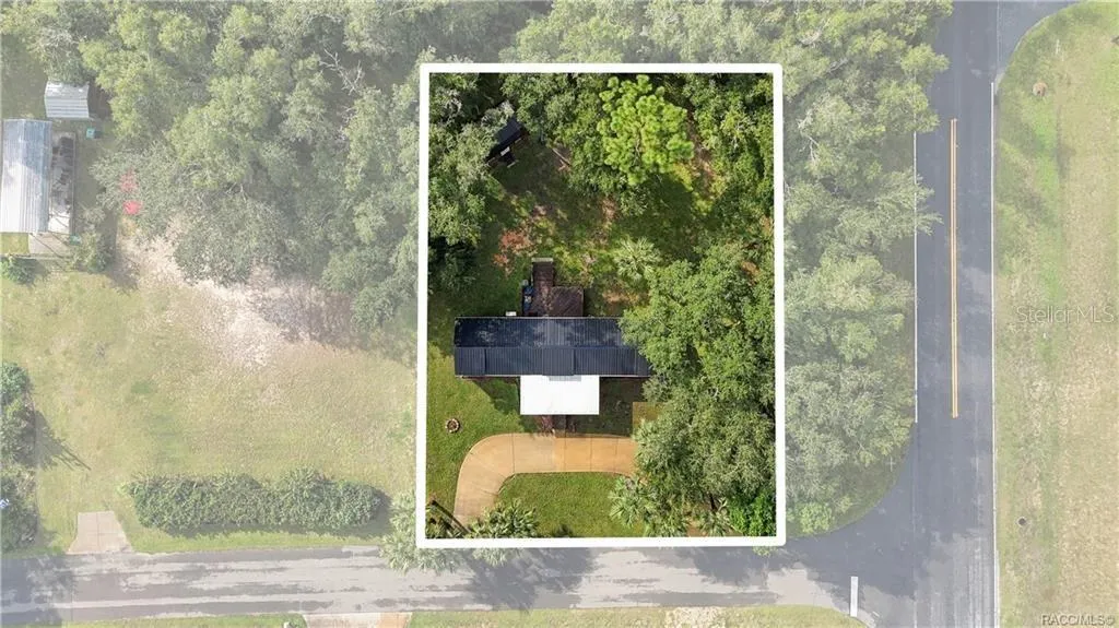 Aerial Property View – Overhead perspective showcasing the home on its .29-ACRE CORNER LOT, surrounded by mature trees, greenery &amp; a circular driveway.