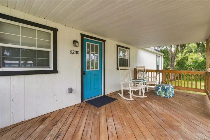 Front Porch Seating – A cozy place to relax, featuring wooden decking, a covered roof &amp; room for rocking chairs to enjoy the Florida breeze.