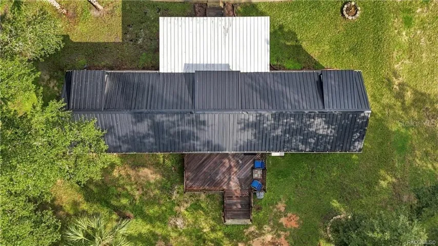 Aerial Roof &amp; Deck View – Bird's-eye perspective showcasing the METAL ROOF, covered front porch, spacious WOODEN REAR DECK &amp; surrounding green space.