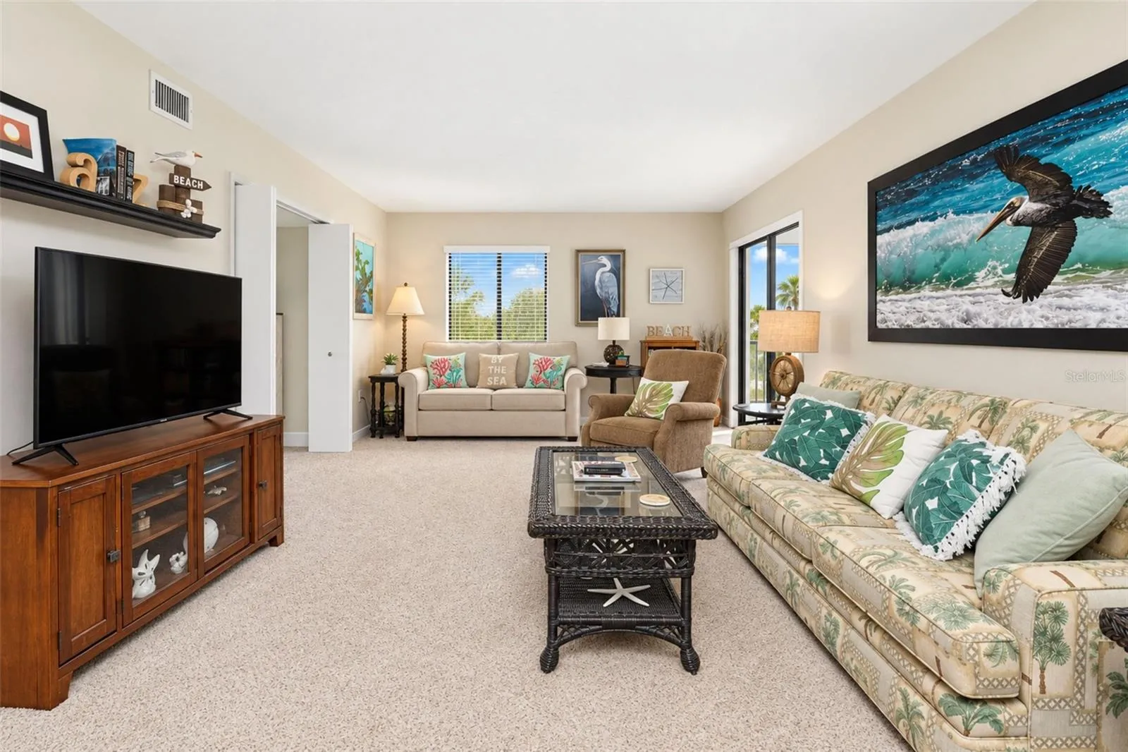 The living room has carpeted flooring and sliding glass doors to the lanai.