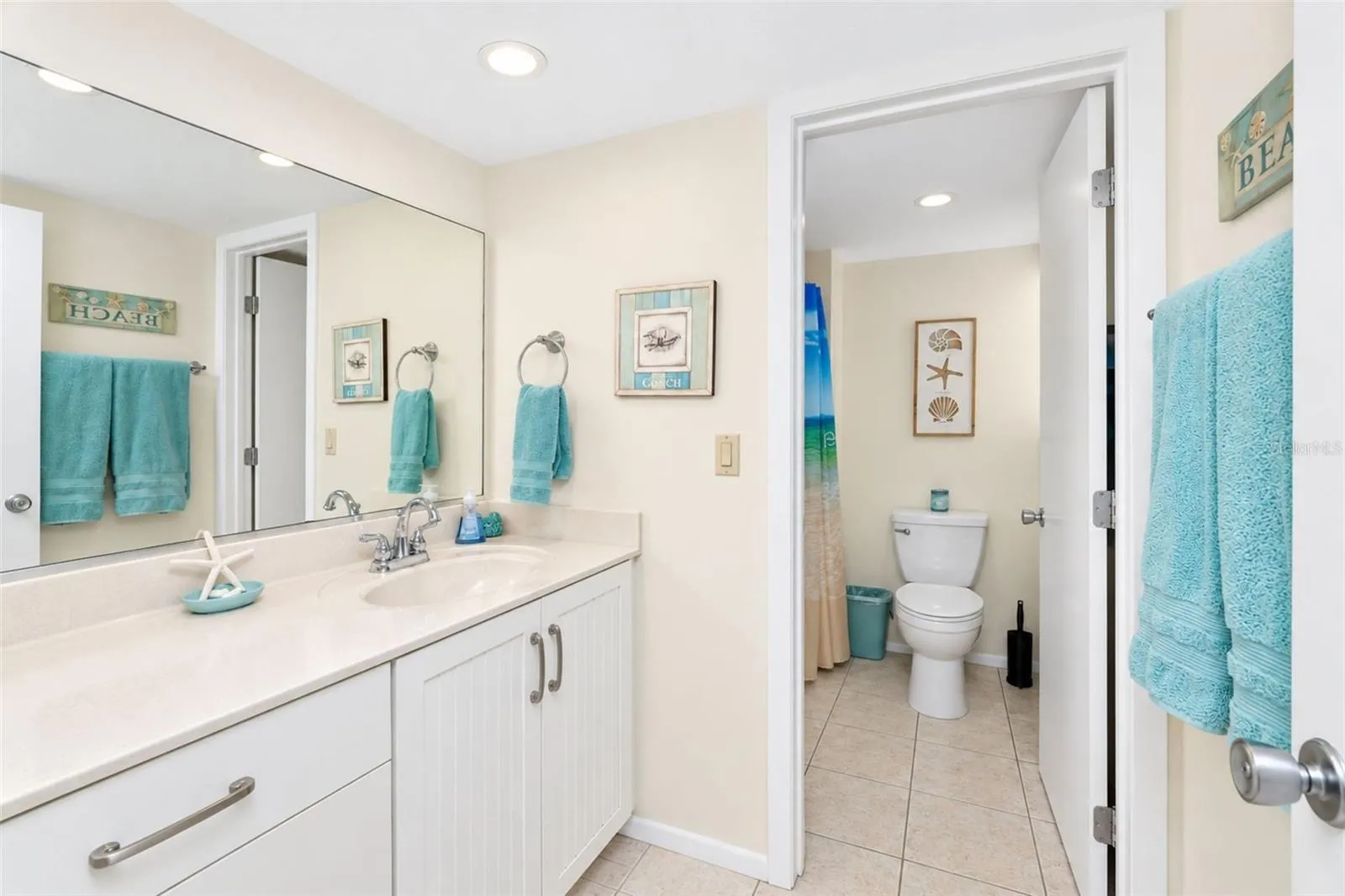 The guest bathroom features tiled flooring and an updated solid surface countertop vanity.