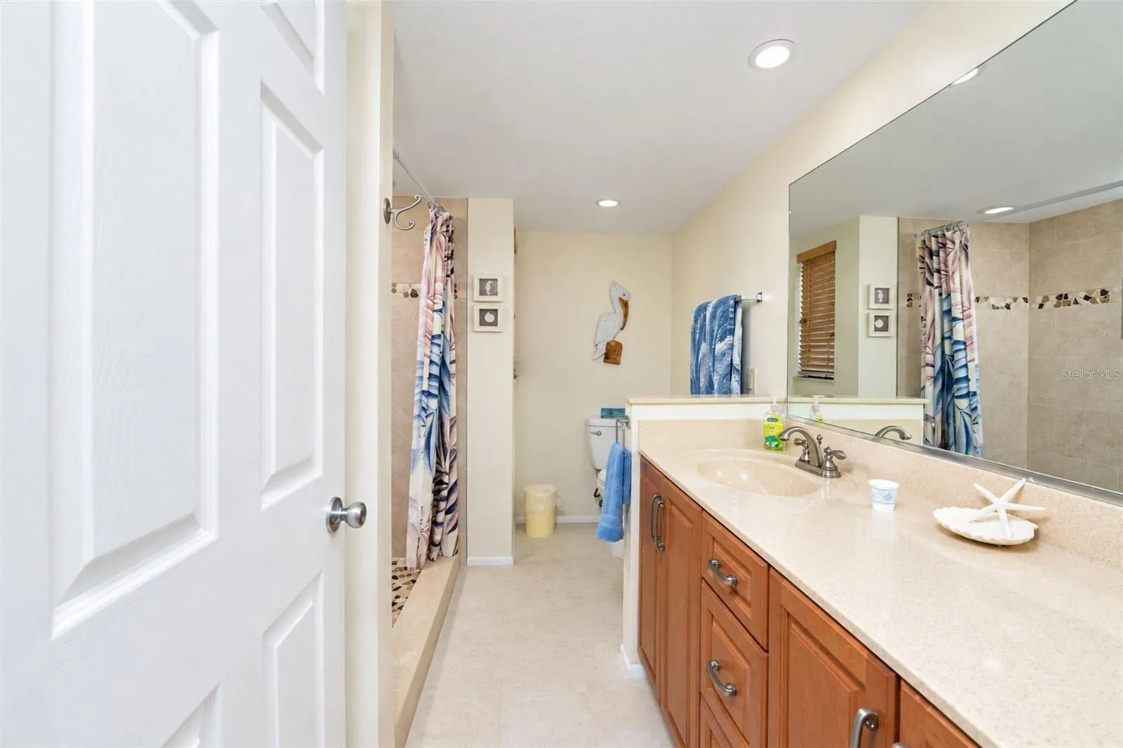 The primary bathroom has a solid surface countertop vanity with plenty of storage and tiled flooring.