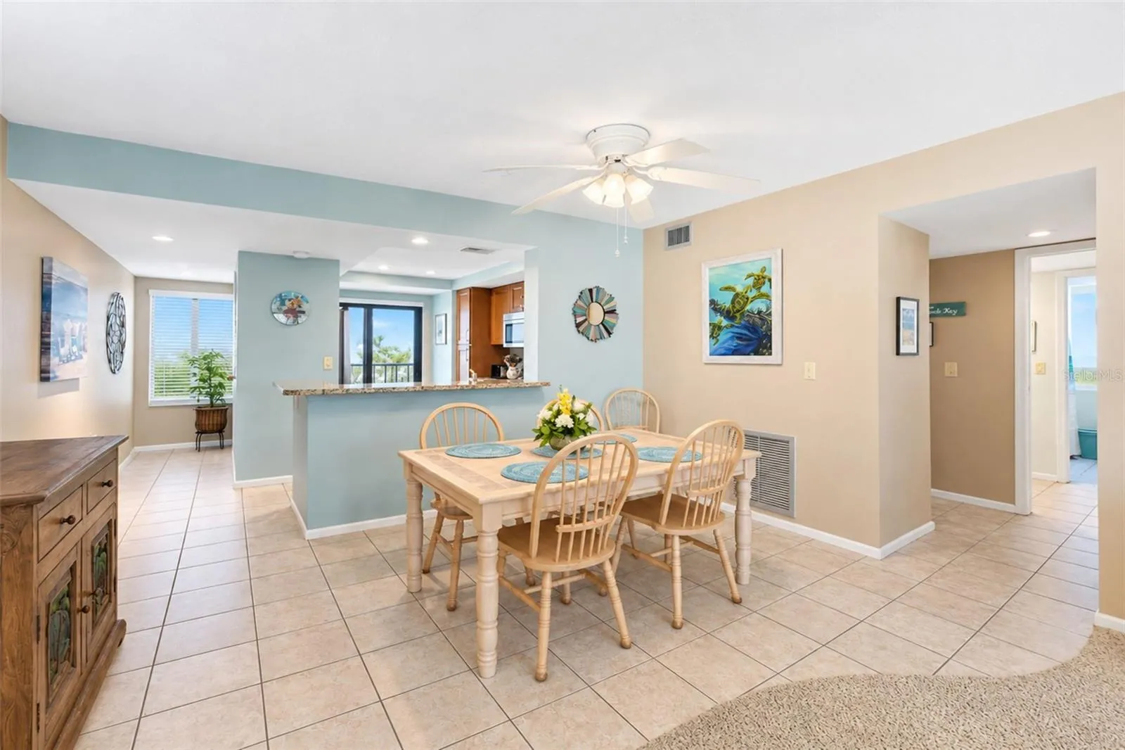 The dining room has tiled flooring and a ceiling fan with light.