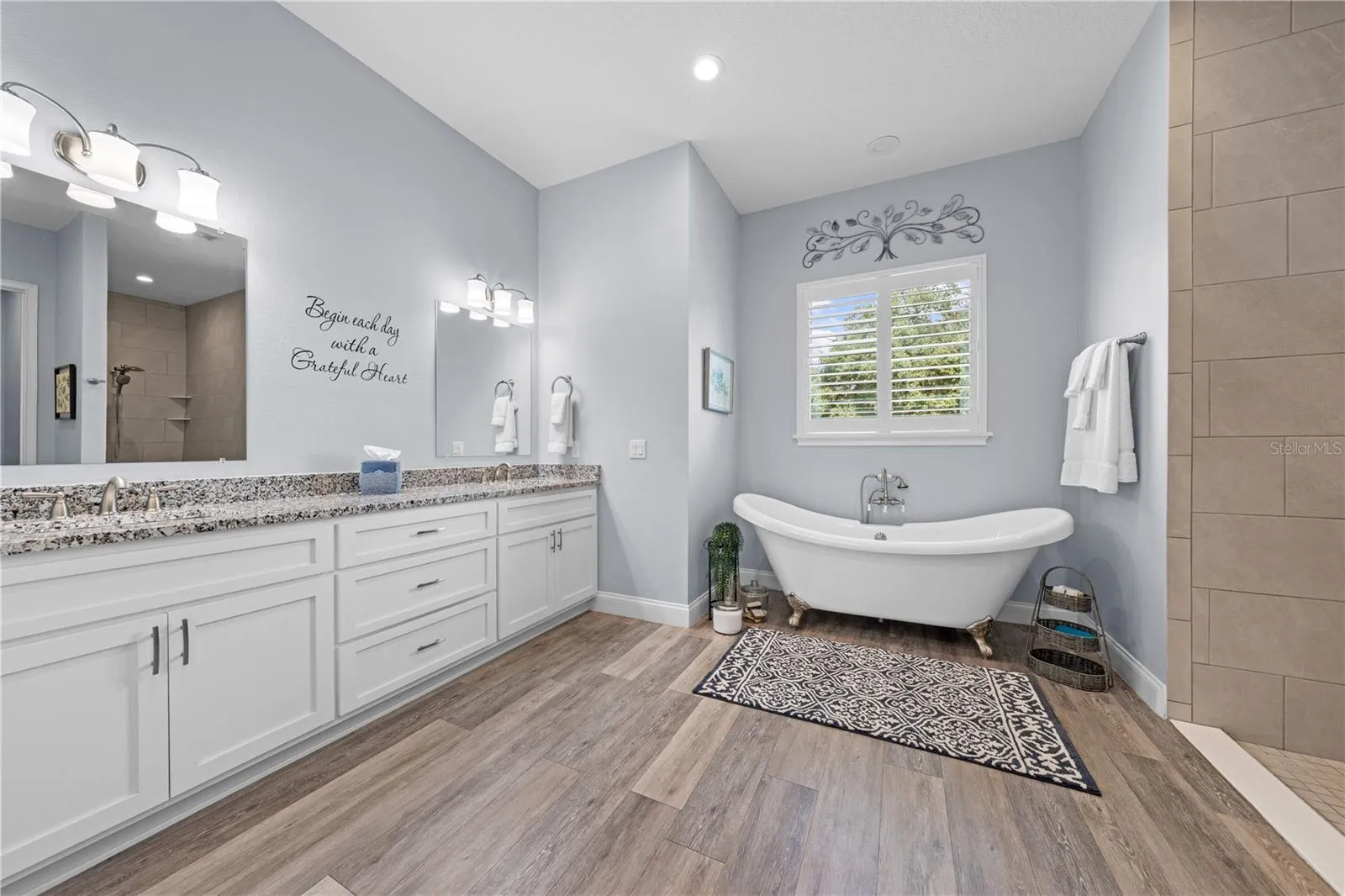 Primary bathroom with claw foot tub and double vanities with granite countertops.