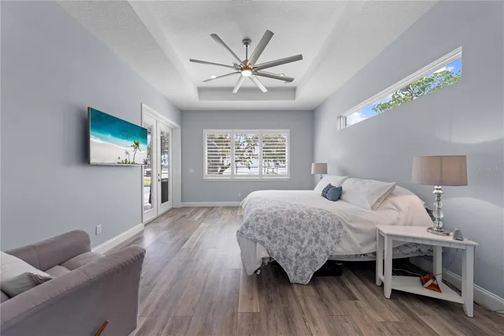 Primary Bedroom with a view of the lake, tray ceiling and double entry doors to the lania