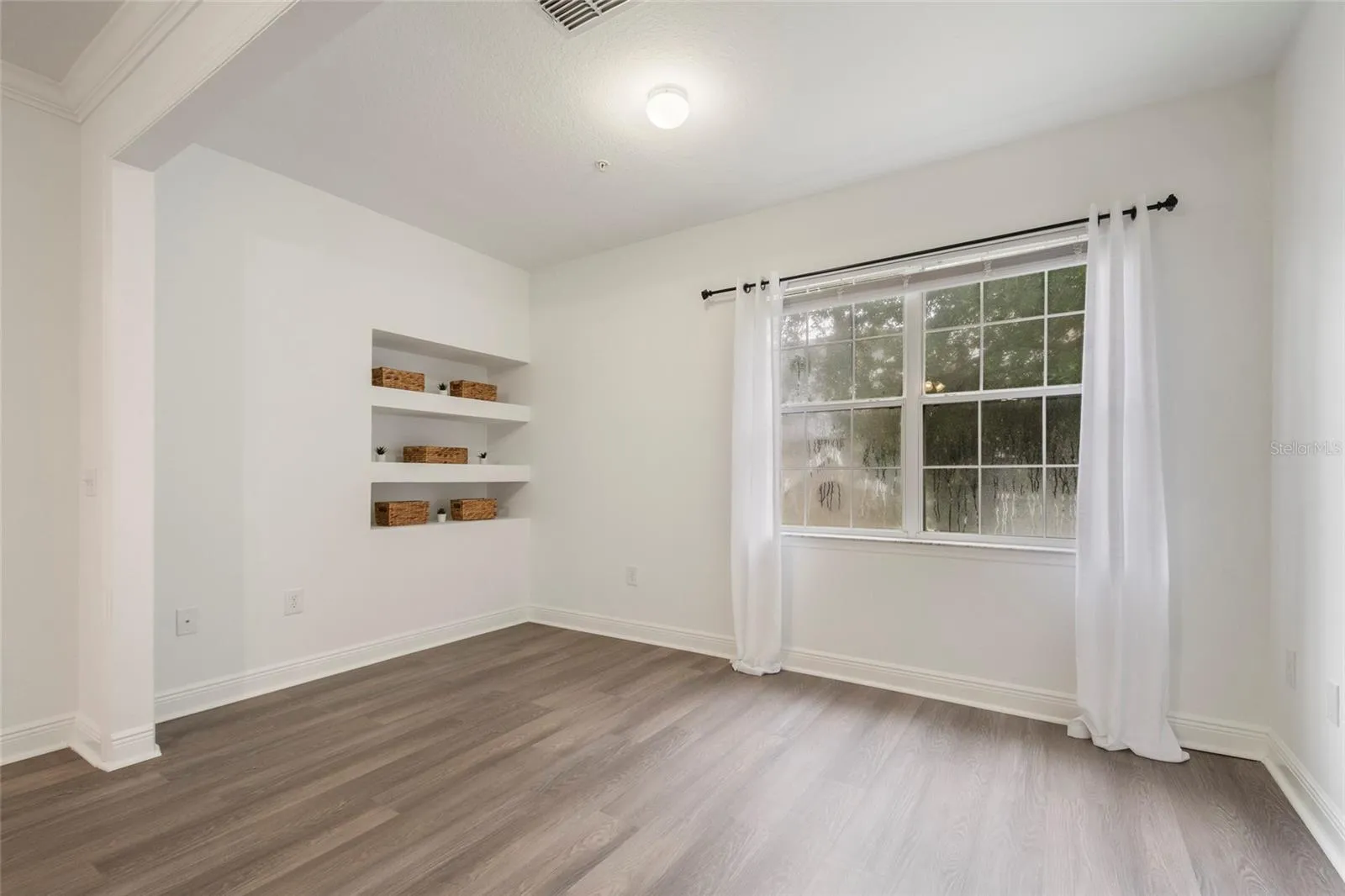 This view shows the built in shelving which would make a great contribution if you chose to dedicate this to a home office or storage space if you chose to make it a flex room for the kids, or work out gear if it became your exercise room. (Drapes do not convey)