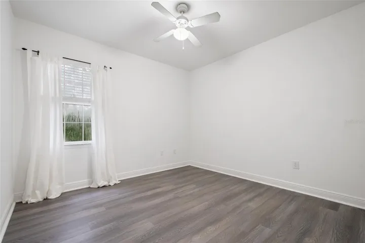 Opposite view of Bedroom 3 towards the window and lovely view of the mature trees. Ceiling fan and drapery rod convey (drapes do not convey)