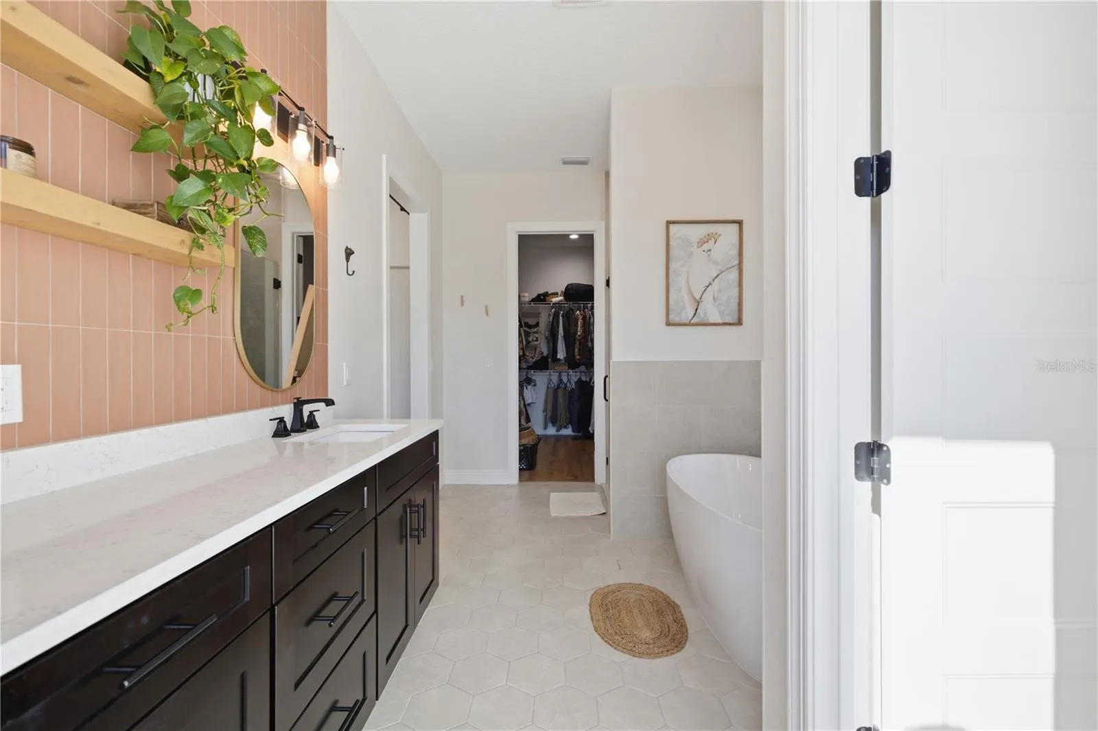 Dual vanity with quartz countertops and freestanding shelving.