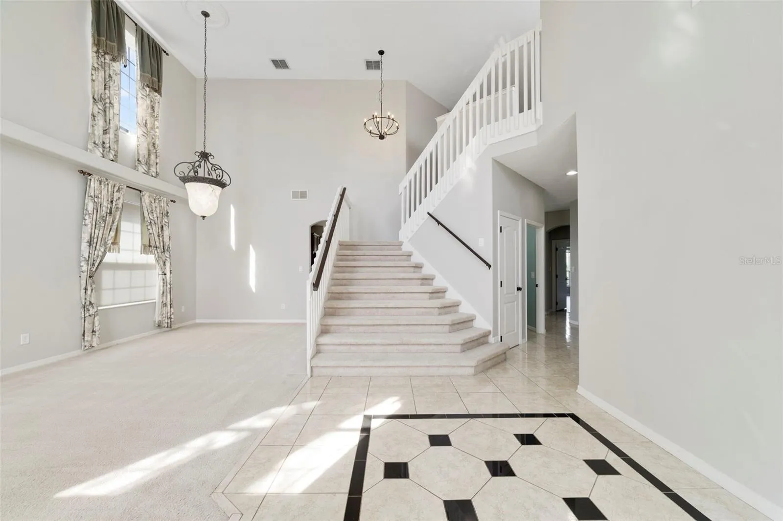 Inside, ETCHED-GLASS FRENCH DOORS open to a welcoming foyer with a SOARING CEILING and decorative tile flooring, setting the stage for the generous living spaces beyond.
