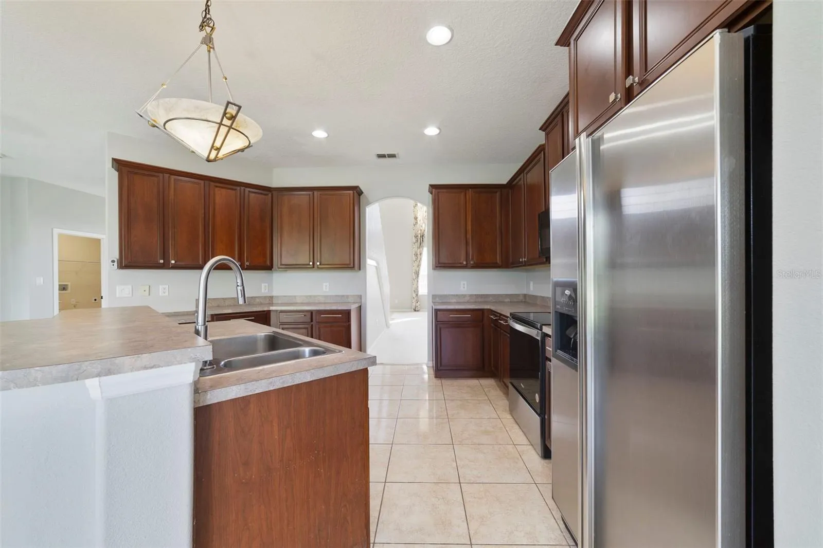 Step through an arched doorway into the spacious Kitchen with ABUNDANT STAGGERED CABINETRY and generous counter space.