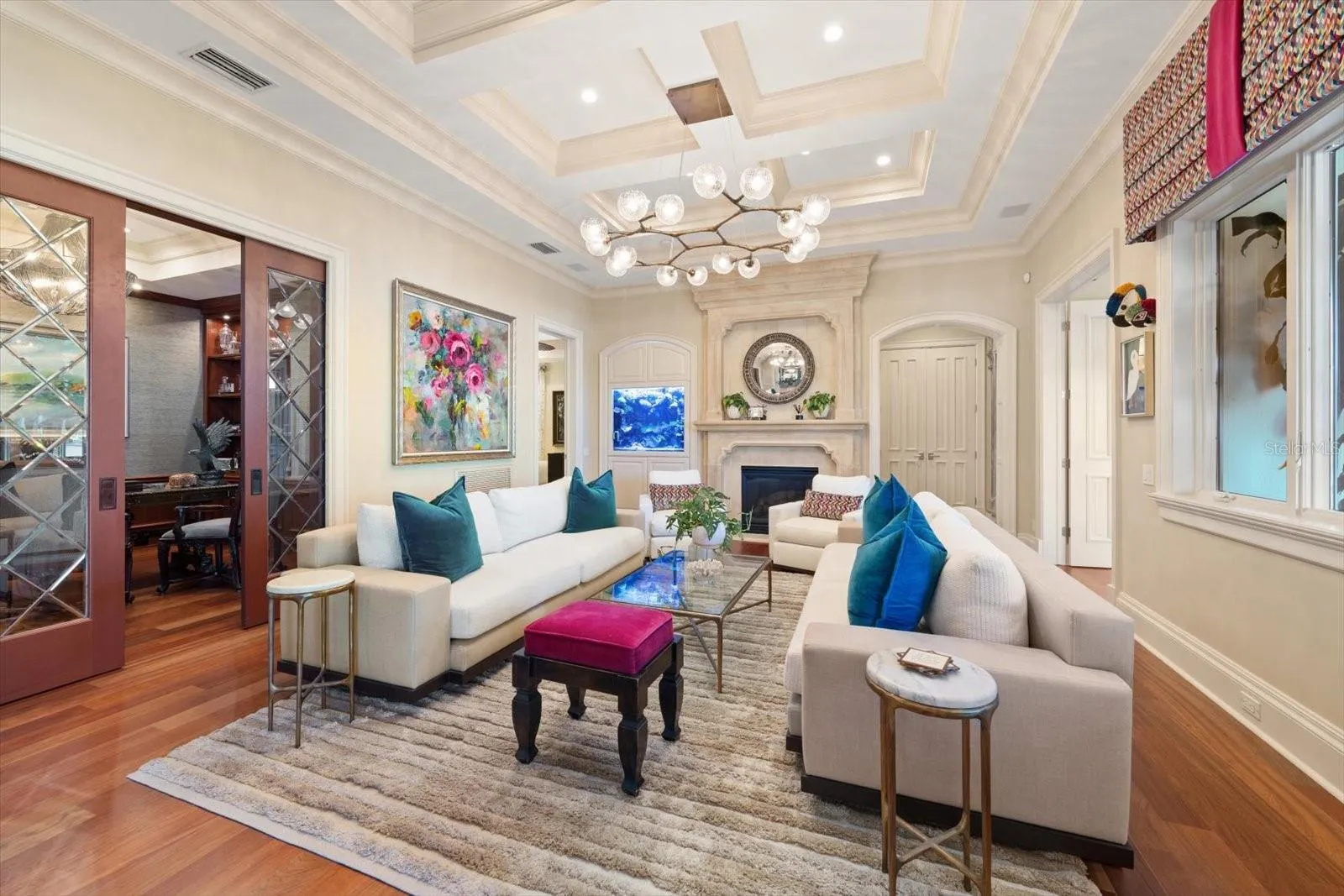 A gas fireplace with a precast stone mantel and a built-in saltwater aquarium in the formal living room