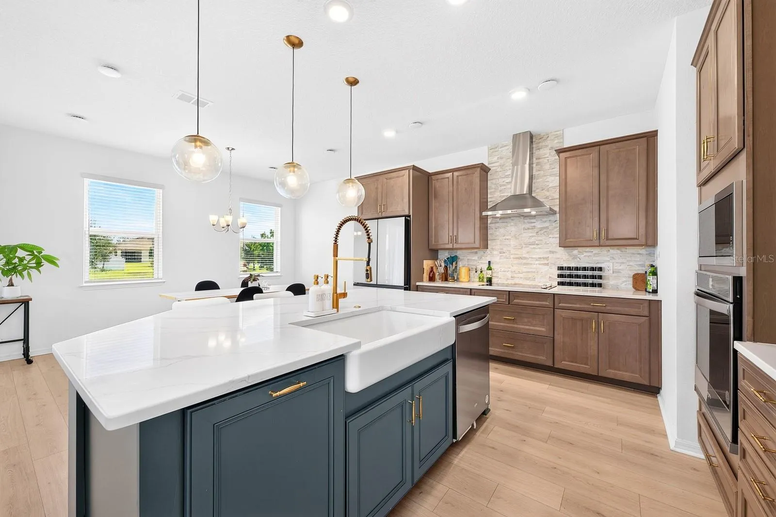 A beautiful BELFAST SINK, built-in oven, sleek cooktop with a CONTEMPORARY RANGE HOOD, and a spacious center island with breakfast bar seating complete this thoughtfully designed space.
