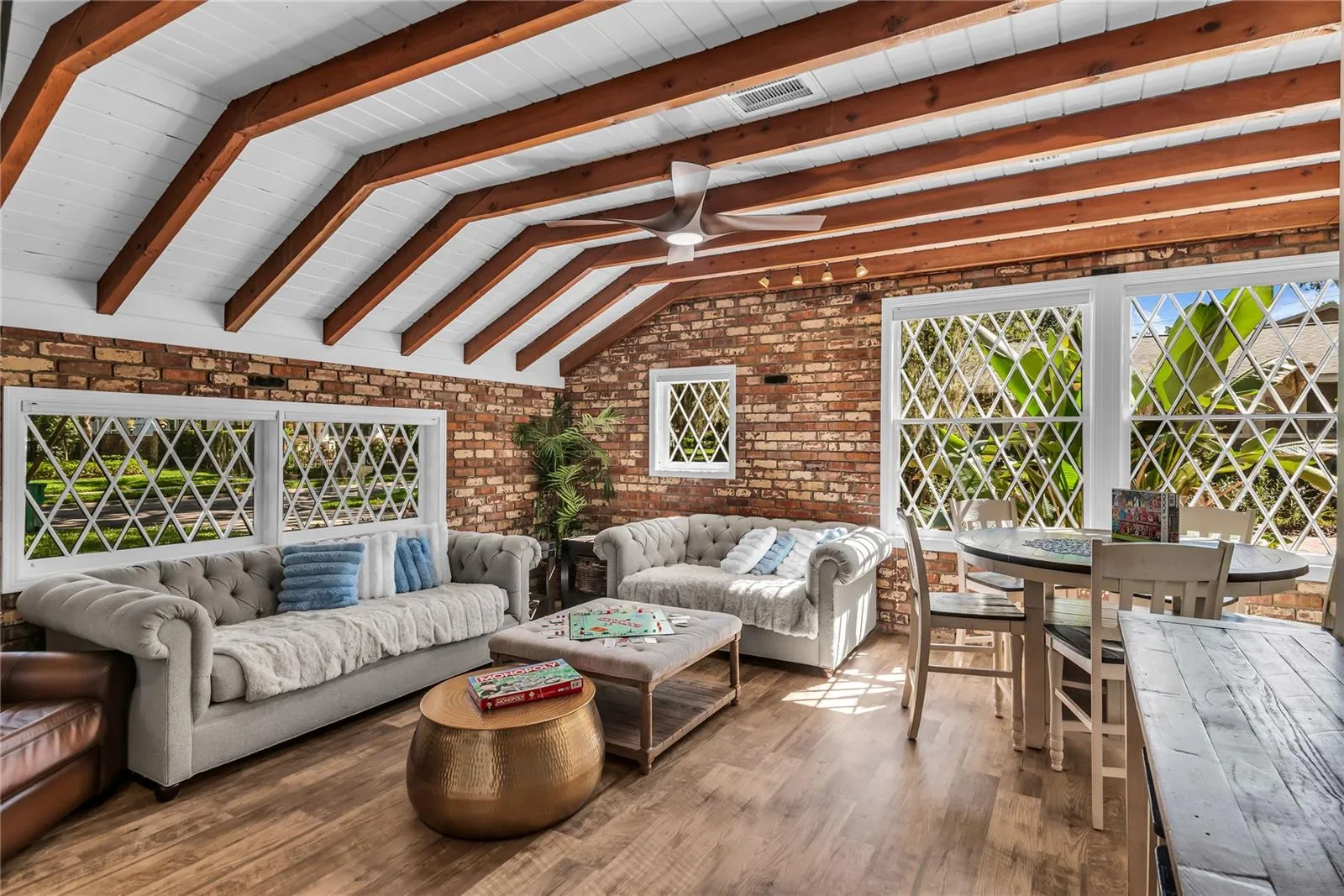 Natural light pours into the spacious family room that features warm brick walls, exposed wood beams and distinctive diamond-pane windows that create a timeless architectural backdrop.