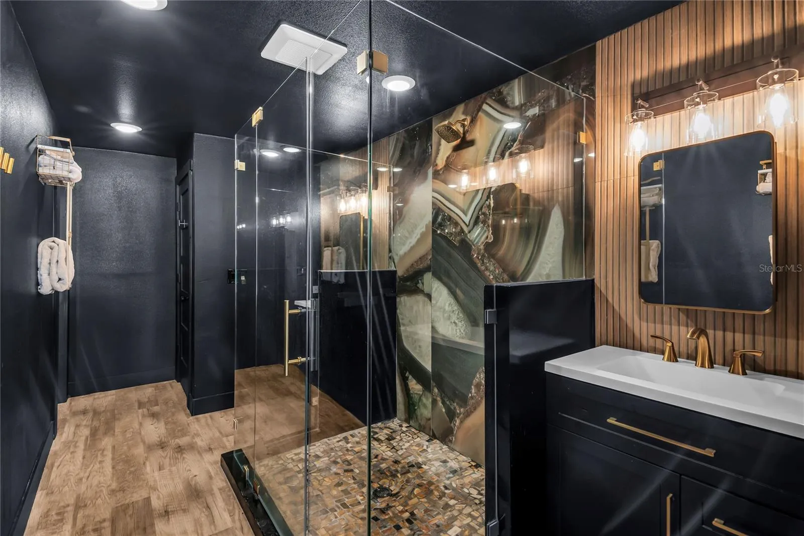 Oversized spa inspired bathroom features with dual vanities, two private water closets, a large glass-enclosed shower and elevated finishes throughout