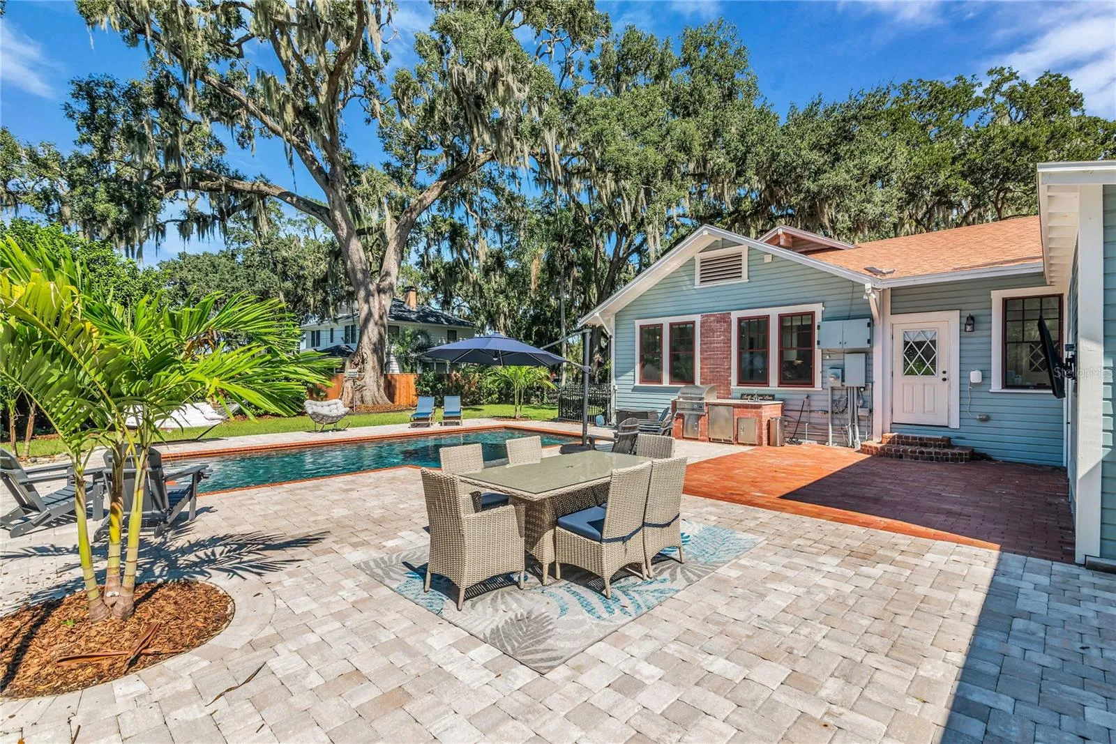 The enormous fully fenced backyard is designed for year-round enjoyment with a gas-heated saltwater sport pool, outdoor kitchen, expansive brick paved deck, detached covered lanai, and low-maintenance turf.