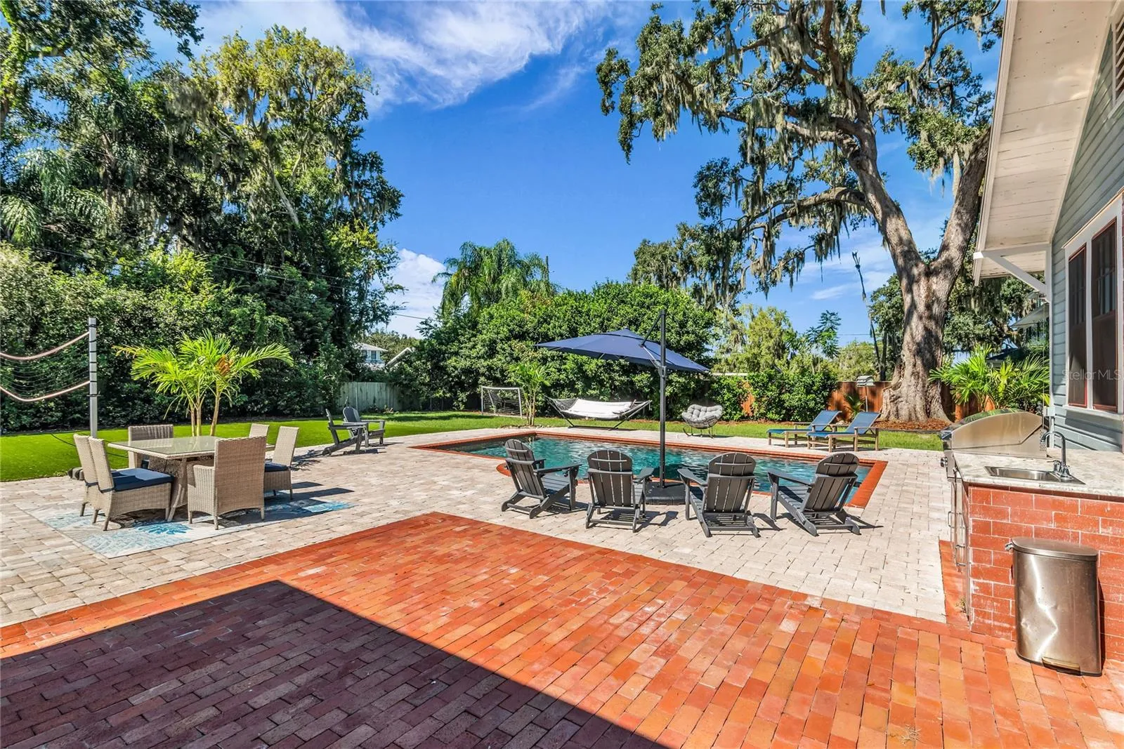 The enormous fully fenced backyard is designed for year-round enjoyment with a gas-heated saltwater sport pool, outdoor kitchen, expansive brick paved deck, detached covered lanai, and low-maintenance turf.