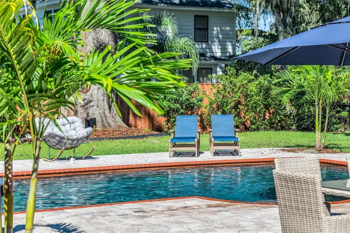 The enormous fully fenced backyard is designed for year-round enjoyment with a gas-heated saltwater sport pool, outdoor kitchen, expansive brick paved deck, detached covered lanai, and low-maintenance turf.