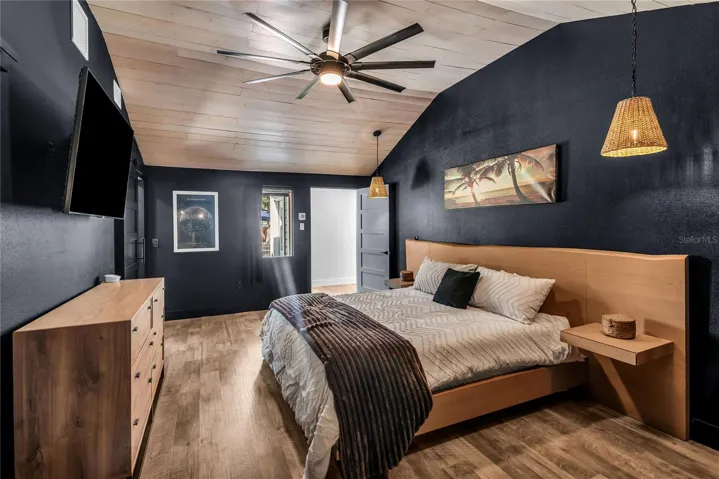 The secluded primary suite blends modern design with inviting comfort, showcasing a striking vaulted plank ceiling, stylish pendant lighting, and an expansive layout. Thoughtfully positioned for privacy, this retreat feels both intimate and spacious, with warm wood accents and sophisticated finishes creating a refined yet relaxing atmosphere.