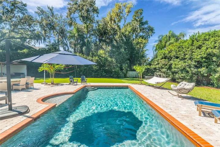 The enormous fully fenced backyard is designed for year-round enjoyment with a gas-heated saltwater sport pool, outdoor kitchen, expansive brick paved deck, detached covered lanai, and low-maintenance turf.