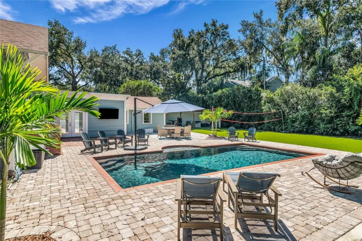 The enormous fully fenced backyard is designed for year-round enjoyment with a gas-heated saltwater sport pool, outdoor kitchen, expansive brick paved deck, detached covered lanai, and low-maintenance turf.
