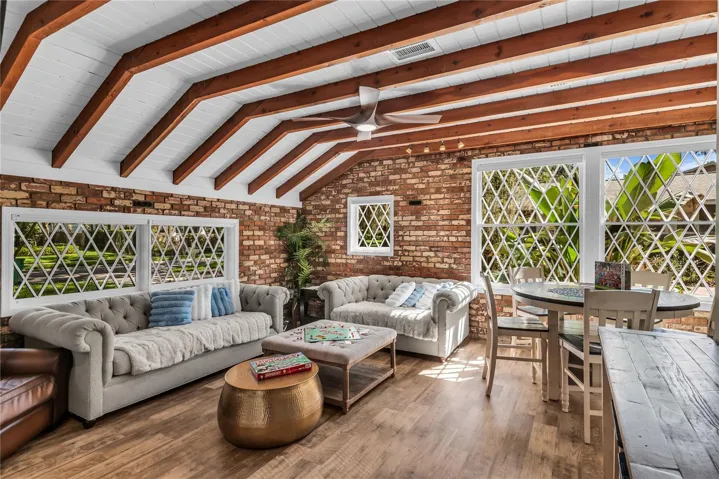 Natural light pours into the spacious family room that features warm brick walls, exposed wood beams and distinctive diamond-pane windows that create a timeless architectural backdrop.