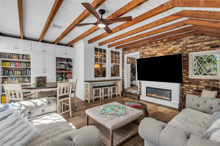 Natural light pours into the spacious family room that features warm brick walls, exposed wood beams and distinctive diamond-pane windows that create a timeless architectural backdrop.