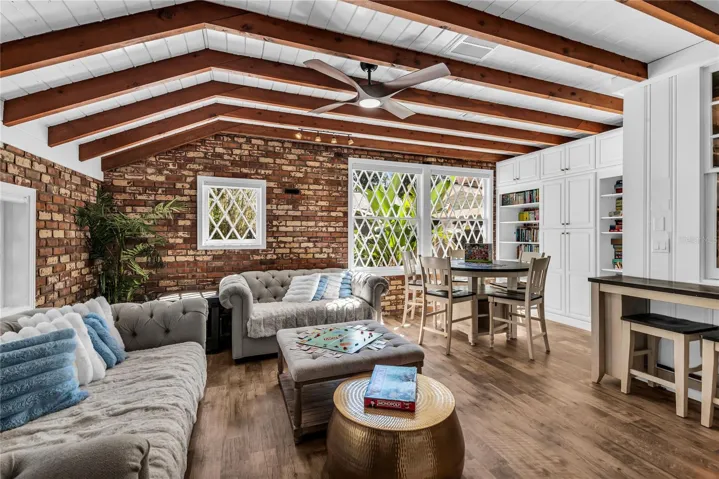 Natural light pours into the spacious family room that features warm brick walls, exposed wood beams and distinctive diamond-pane windows that create a timeless architectural backdrop.
