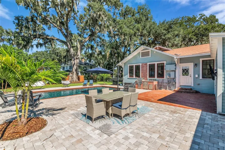 The enormous fully fenced backyard is designed for year-round enjoyment with a gas-heated saltwater sport pool, outdoor kitchen, expansive brick paved deck, detached covered lanai, and low-maintenance turf.