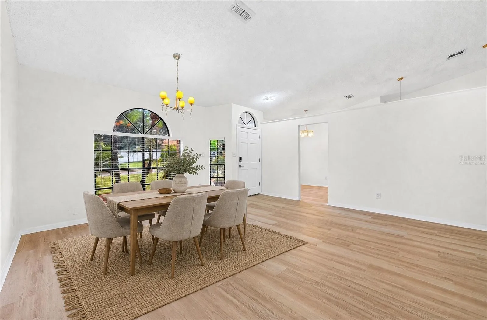 The formal Dining Room features an ELEGANT ARCHED LUNETTE WINDOW and flows into the Living Room. Virtually Staged