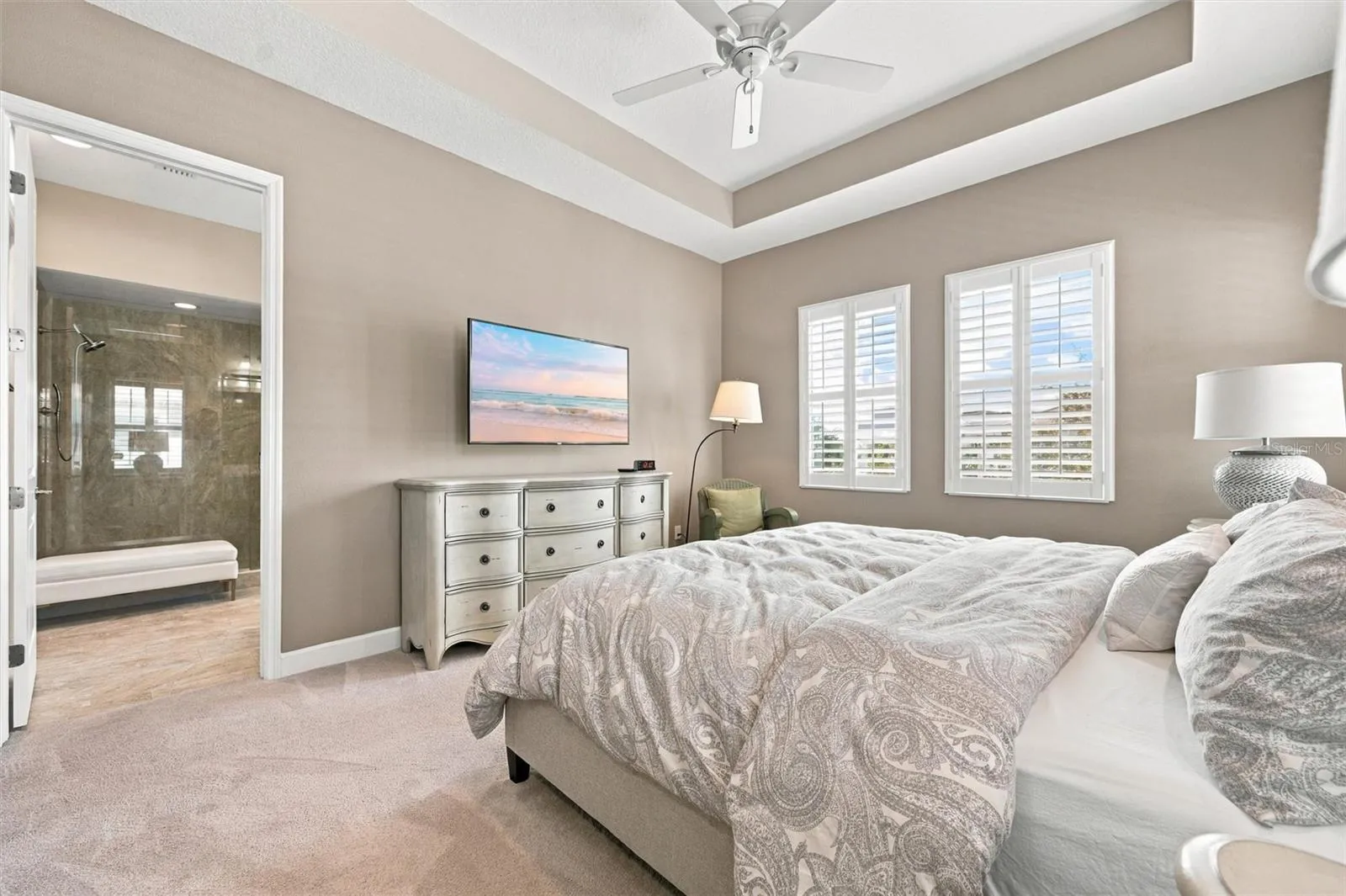spacious primary suite, featuring an elegant tray ceiling and two walk-in closets for ample storage.