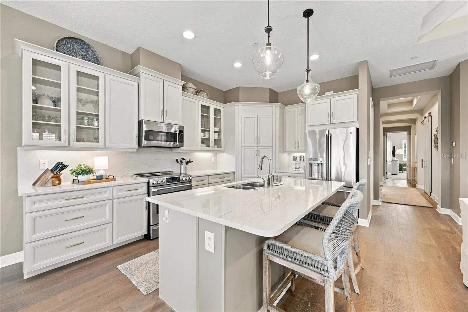 The well-designed kitchen shines with GE Café stainless steel appliances, elegant quartz countertops, and a spacious walk-in pantry.