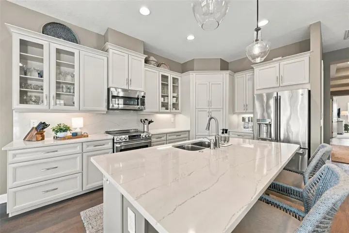 The well-designed kitchen shines with GE Café stainless steel appliances, elegant quartz countertops, and a spacious walk-in pantry.