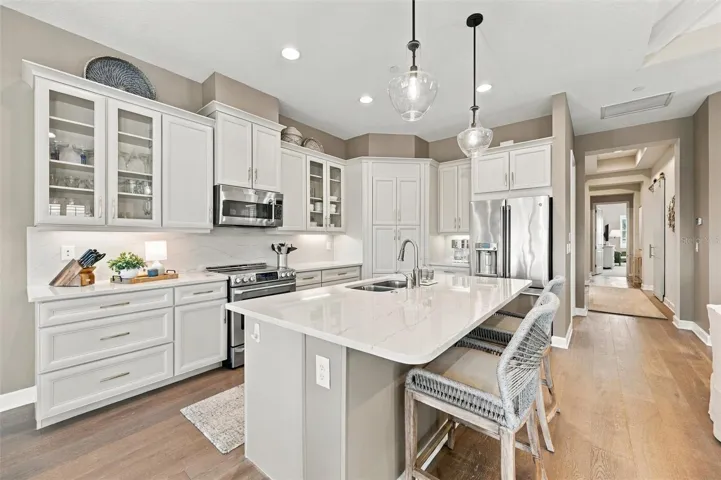 The well-designed kitchen shines with GE Café stainless steel appliances, elegant quartz countertops, and a spacious walk-in pantry.
