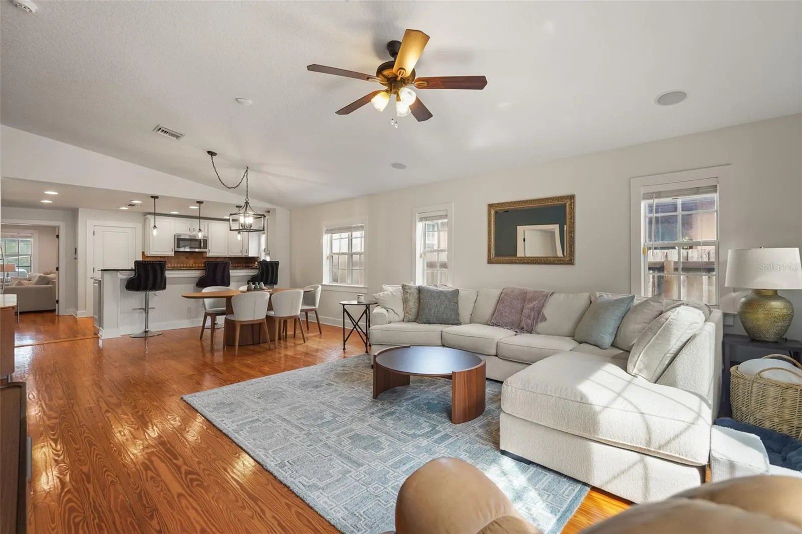 Living room with vaulted ceiling open to the dining area and kitchen