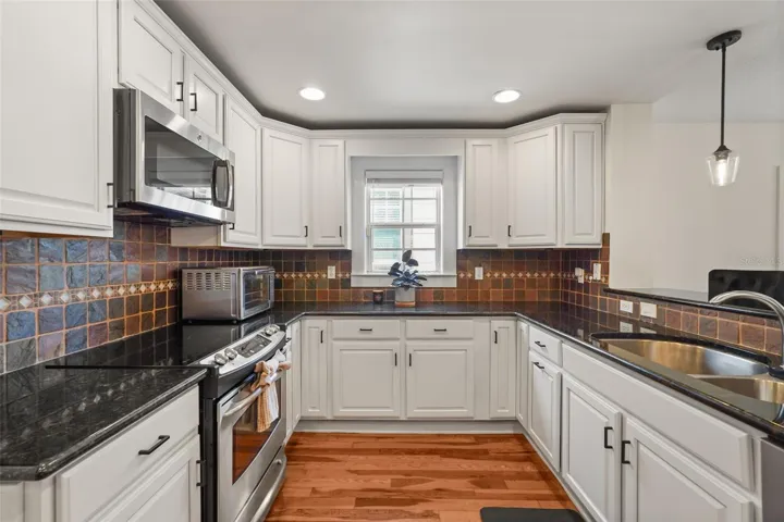 Kitchen with white cabinetry, stainless steel appliances, and tile backsplash