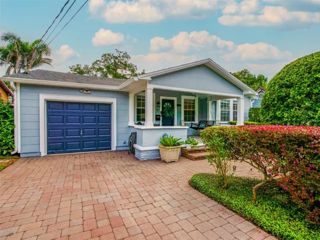 Front exterior with paver driveway, covered front porch, and attached garage