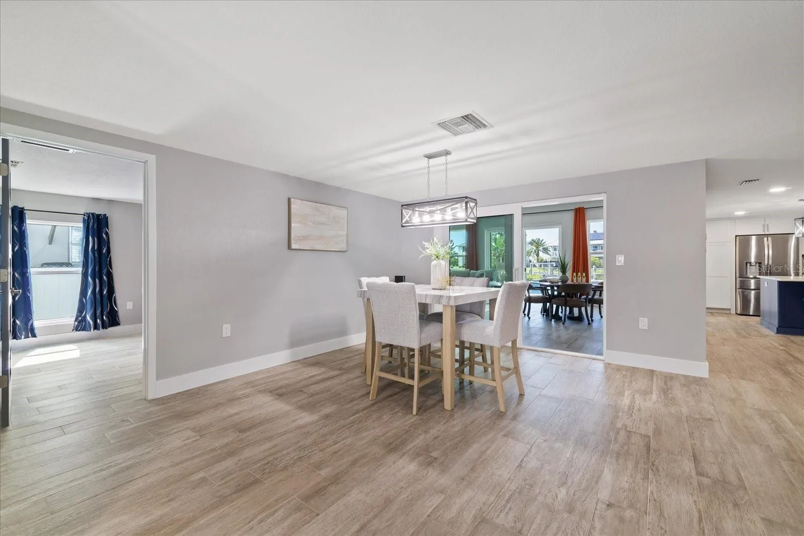 View from entry of primary bedroom entry and family room sliders past dining table