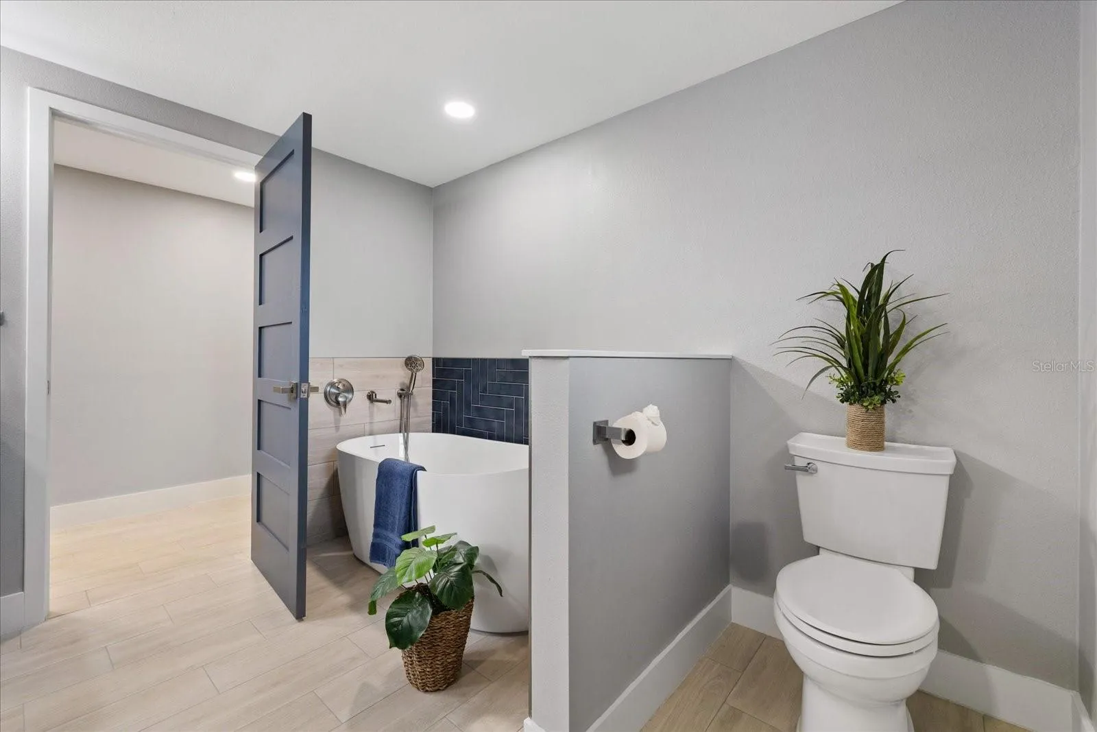 Opening to extra large walk in closet in primary bathroom with divided wall near tub