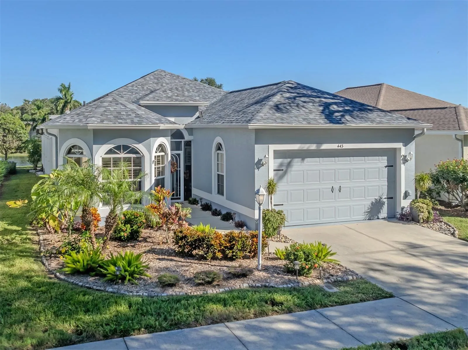 Beautiful curb appeal welcomes you home, featuring a charming bay window, lush mature landscaping, and a lovely glimpse of the peaceful lake beyond!