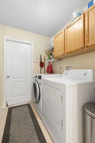 Even laundry day gets a little easier! This dedicated laundry room keeps everything organized with a full-size washer and dryer, overhead cabinetry, and additional shelving for everyday essentials.