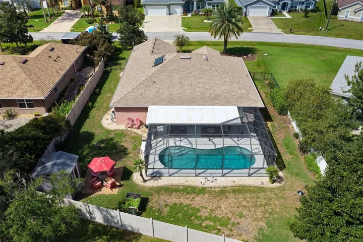 A backyard designed for making memories! This aerial view showcases the screened pool, spacious fenced yard, charming she shed, and outdoor gathering areas, offering plenty of ways to enjoy Florida living.
