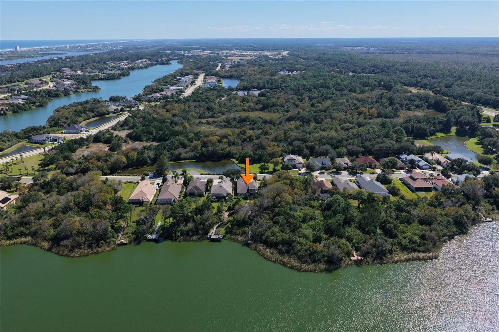 Aerial perspective showcasing the home's location along Emerald Lake, surrounded by natural greenery within Palm Coast Plantation.