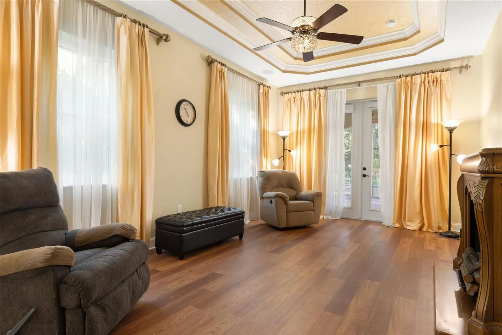 A spacious first-floor primary retreat featuring an elegant tray ceiling, abundant natural light and French doors opening to the screened lanai.