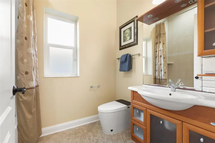 Italian-inspired first-floor guest bathroom featuring distinctive wood cabinetry, decorative tile flooring, and a tub/shower combination.